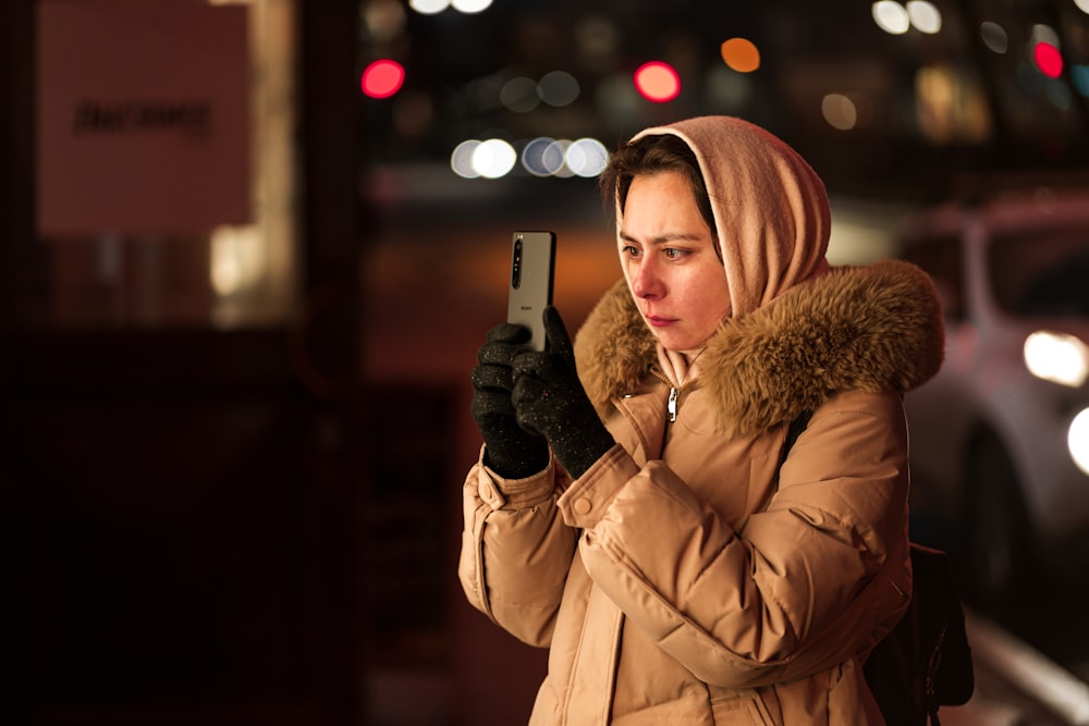a woman in a parka looking at her cell phone
