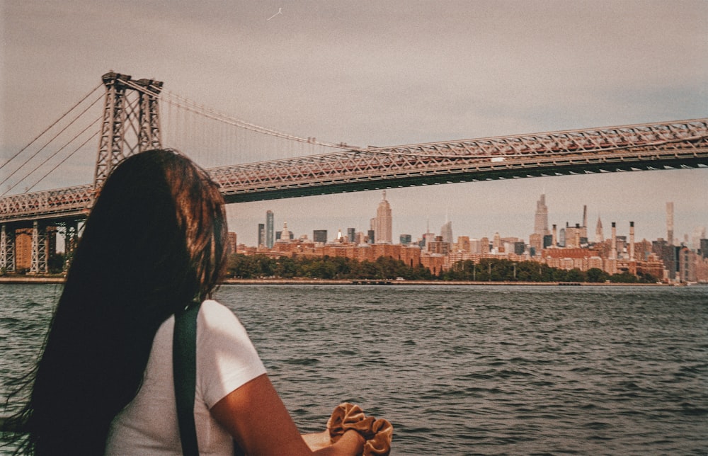 a woman sitting on a boat in front of a bridge