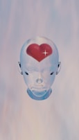 A transparent, futuristic robotic head is centered against a soft gradient background. Inside the head, at the forehead, is a realistic red heart with a shining star-like sparkle.
