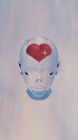 A transparent, futuristic robotic head is centered against a soft gradient background. Inside the head, at the forehead, is a realistic red heart with a shining star-like sparkle.