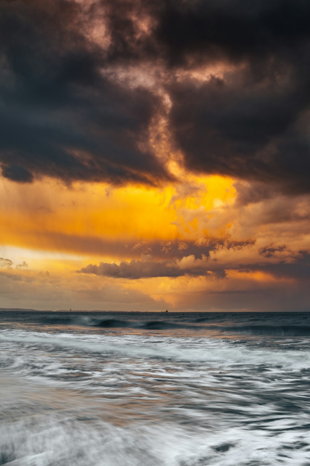 a cloudy sky over the ocean with waves