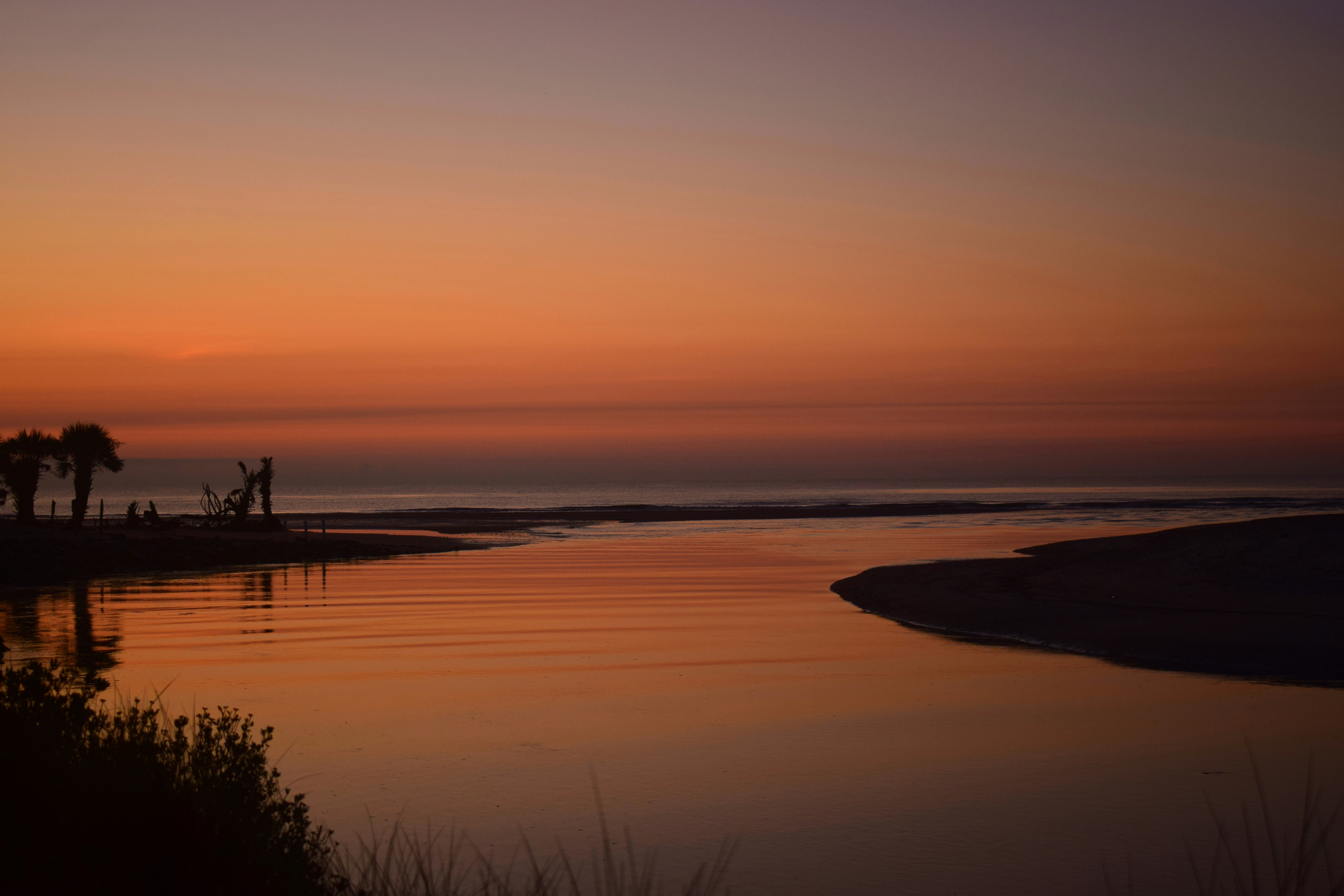 a body of water with a sunset in the background