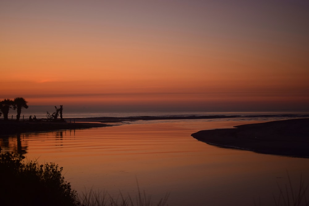 a body of water with a sunset in the background