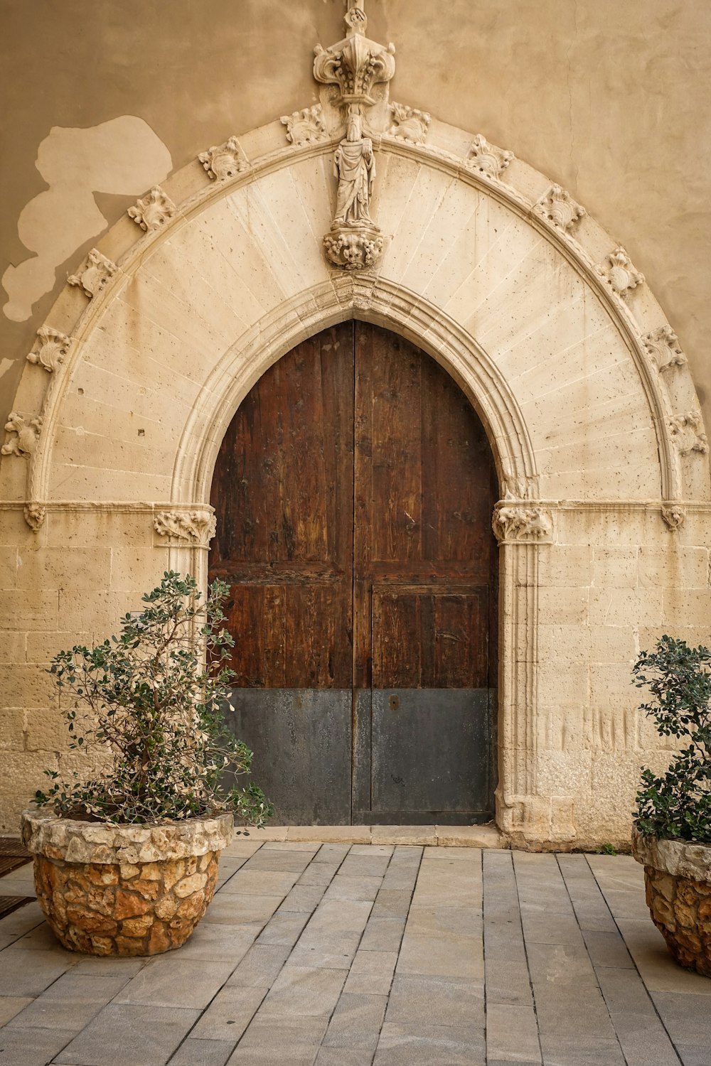 a large wooden door with two planters in front of it