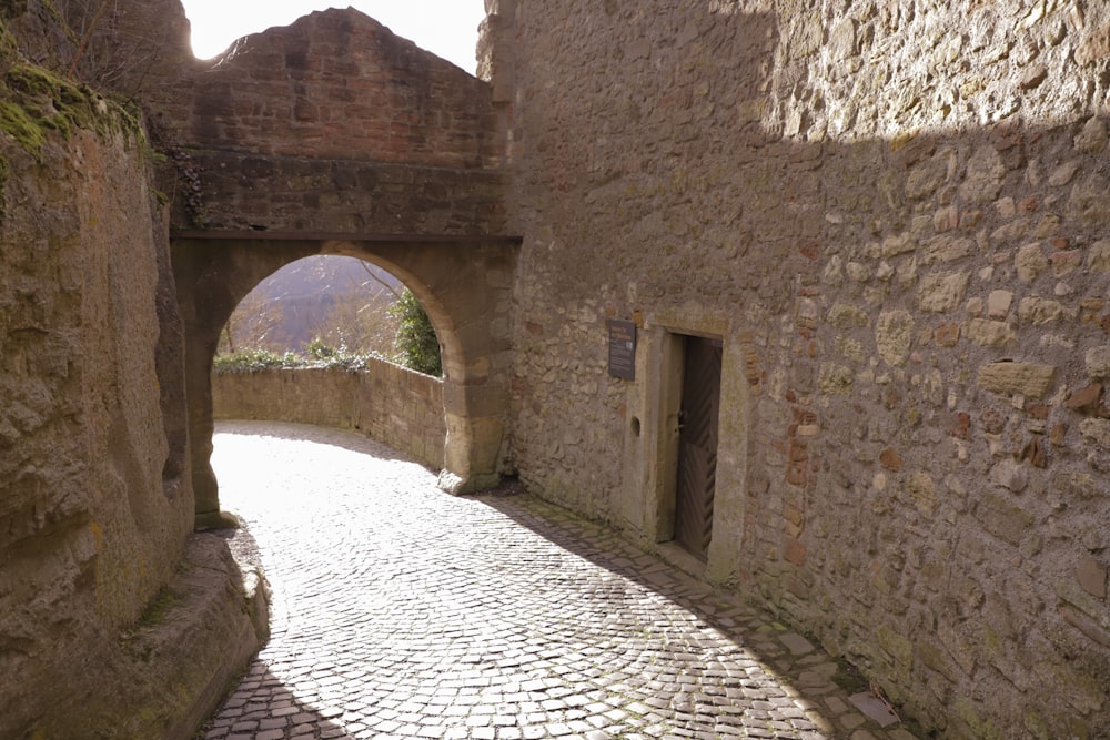 a cobblestone street with a stone arch between two buildings