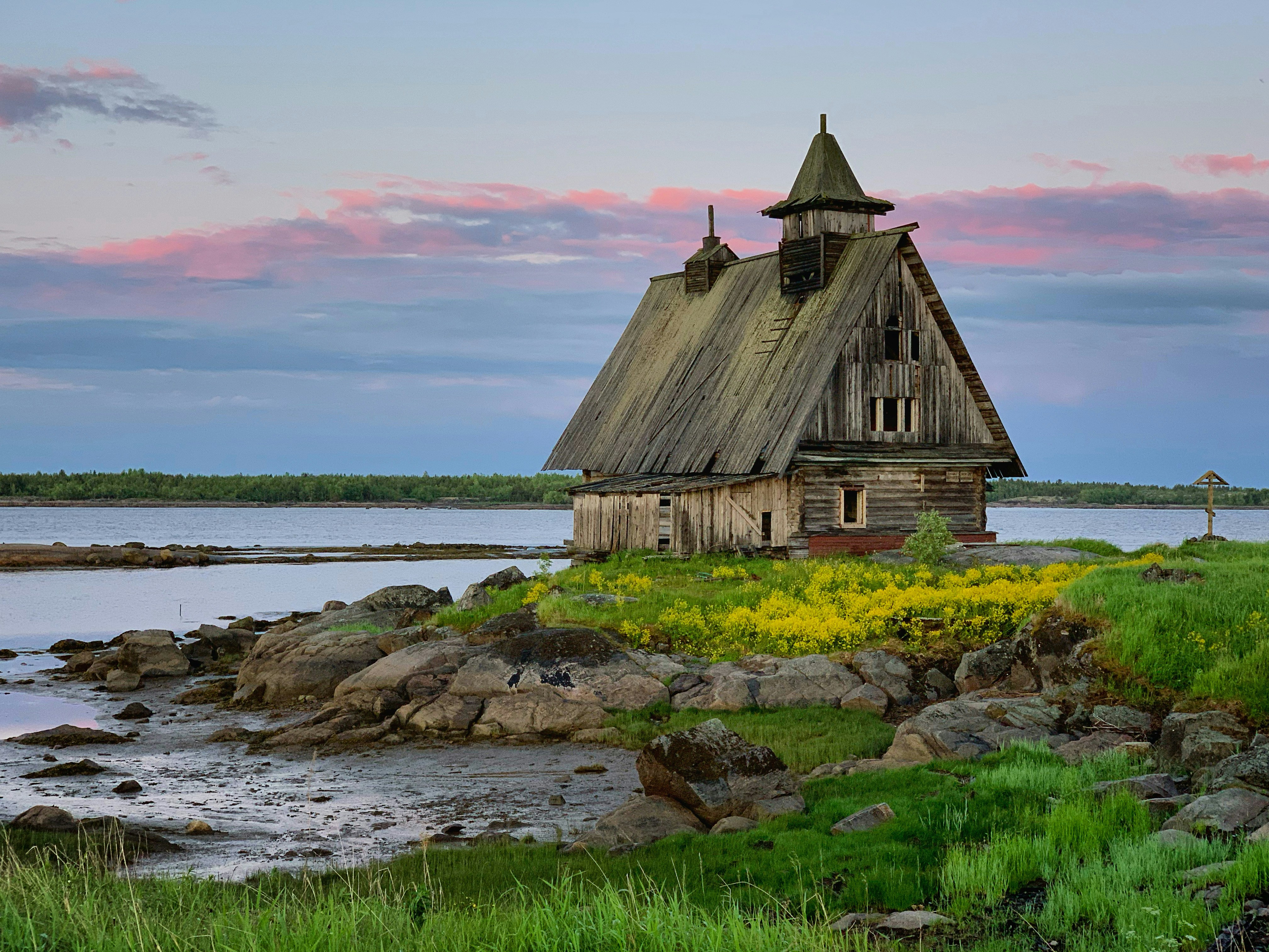 an old wooden building sitting on top of a lush green field