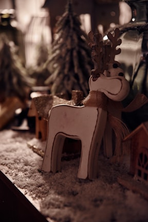 Close-up of elegant reindeer figurines surrounded by pine cones and soft fairy lights on a wooden mantel.