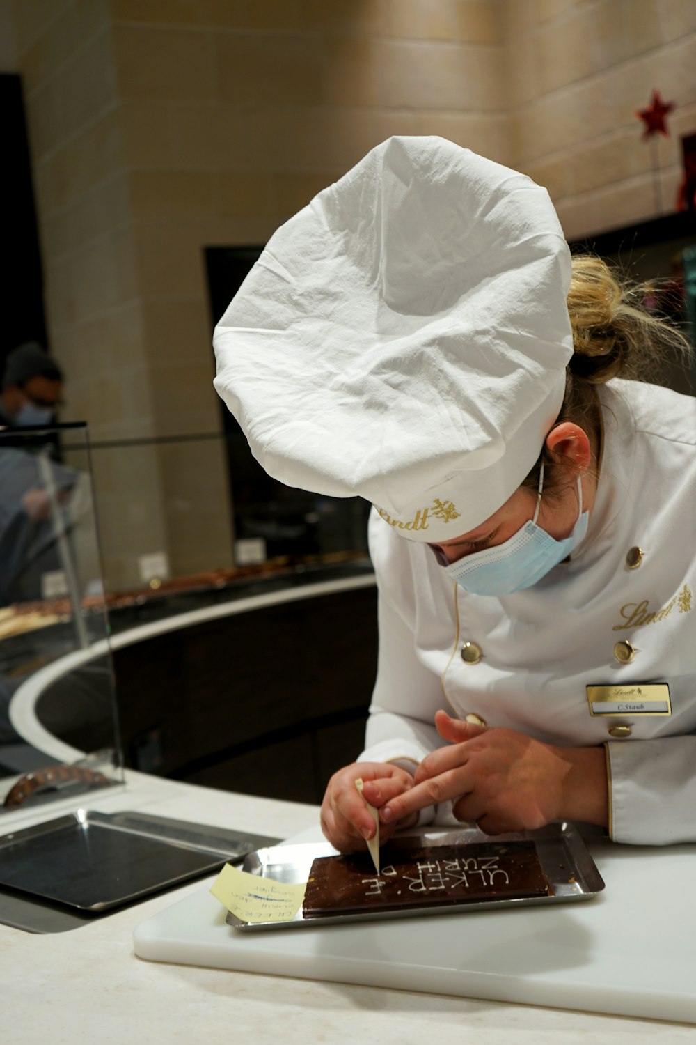 a woman in a chef's hat is cutting a piece of cake
