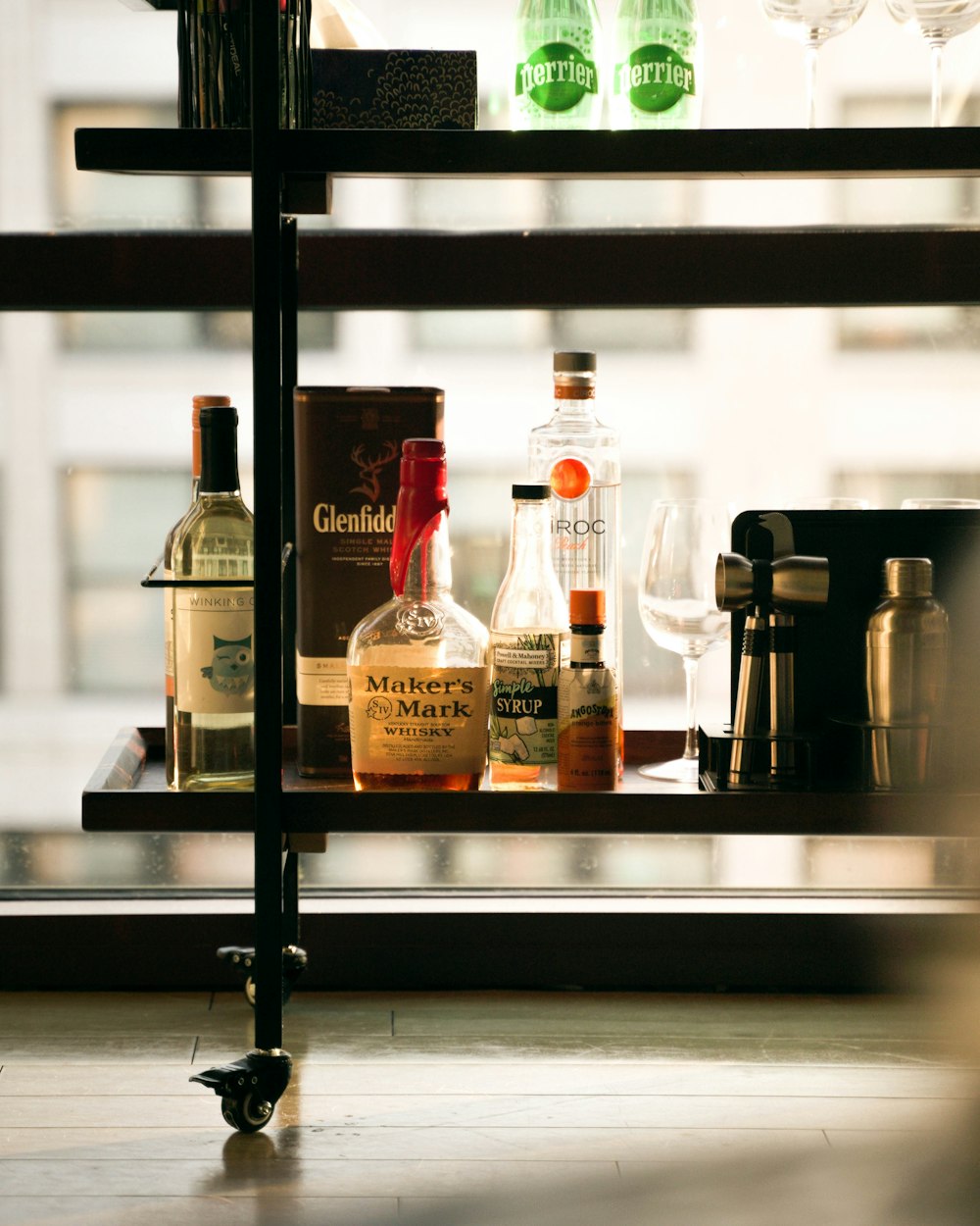 a shelf filled with bottles of alcohol next to a window