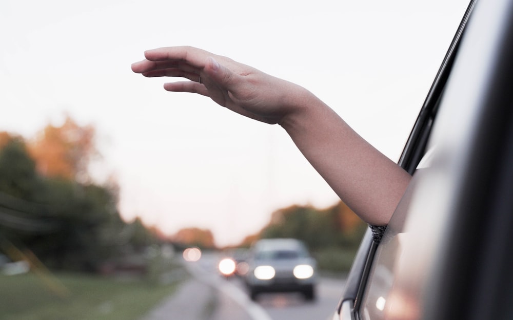 a hand reaching out of a car window