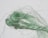 A close-up image of a bundle of fibrous material, with twisted and loose strands. The fibers appear green and have a shiny, textured appearance against a light background.