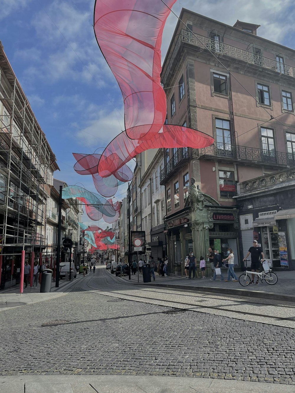 a large red and white kite flying over a street