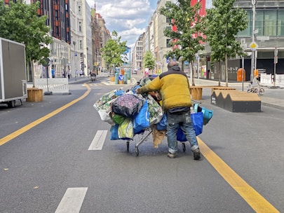 a man pushing a cart full of bags down a street