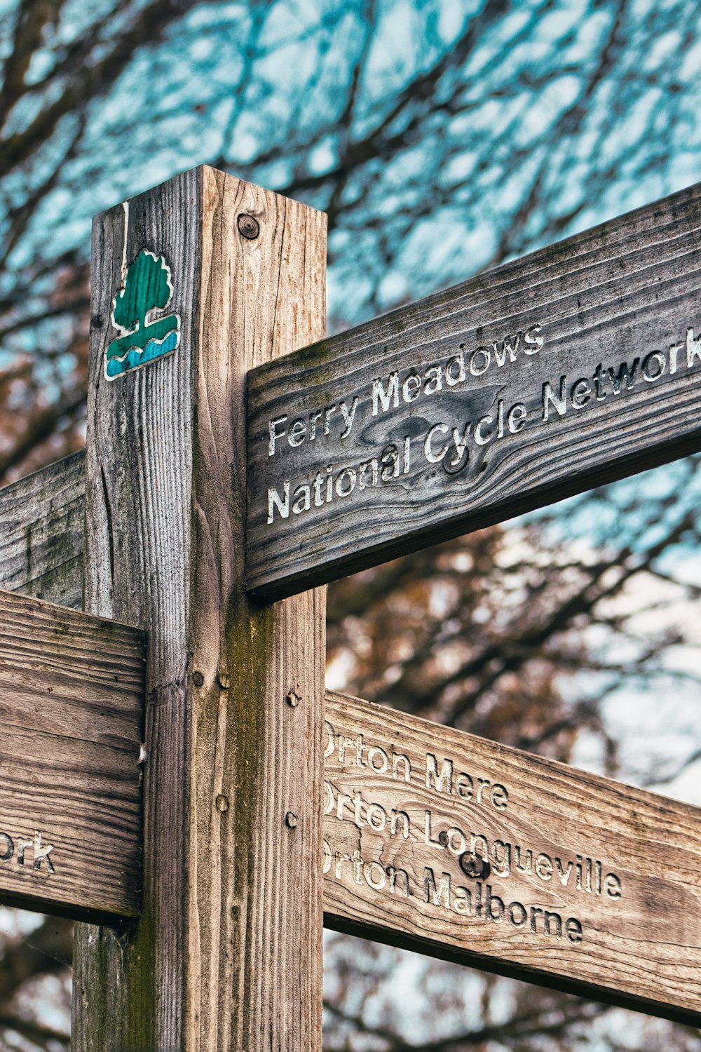 a close up of a wooden sign with trees in the background