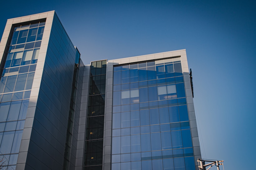 Modern office building exterior with nile blue and grey goose color accents under a clear sky.