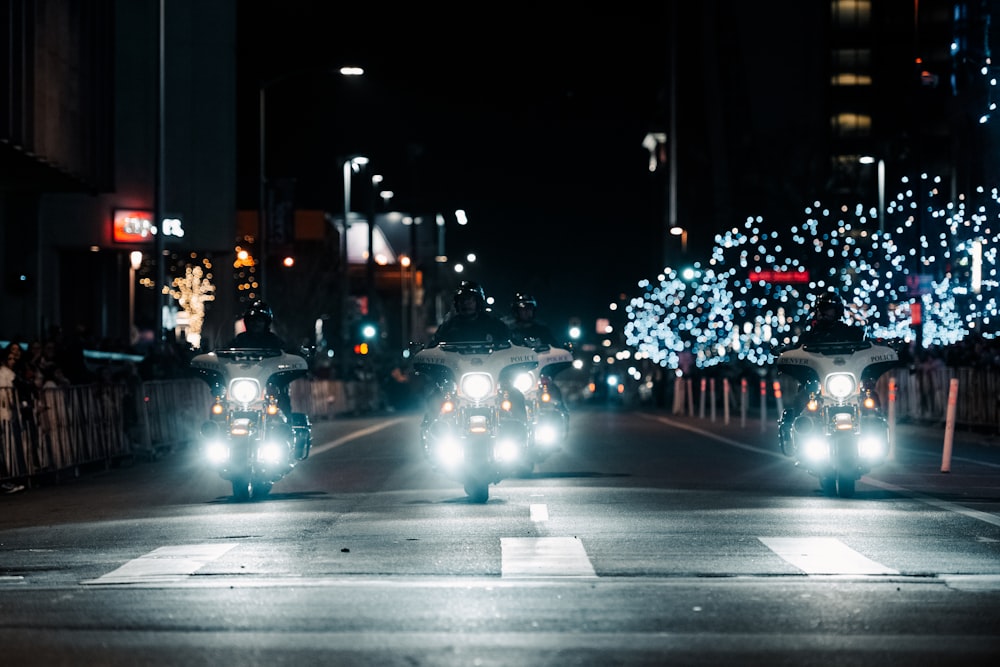 a couple of cars driving down a street at night