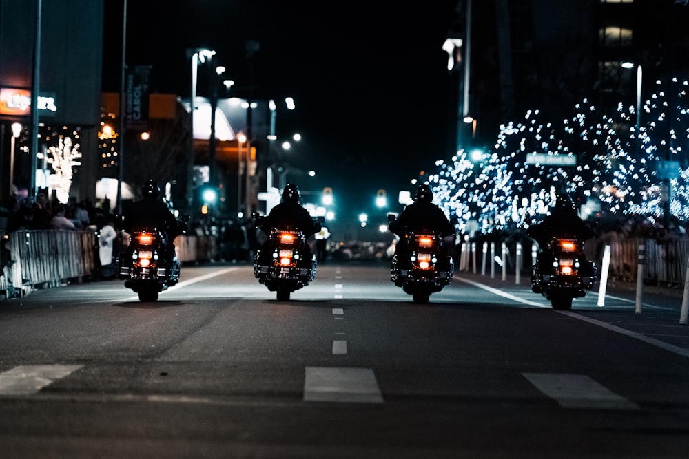 a couple of motorcycles driving down a street at night