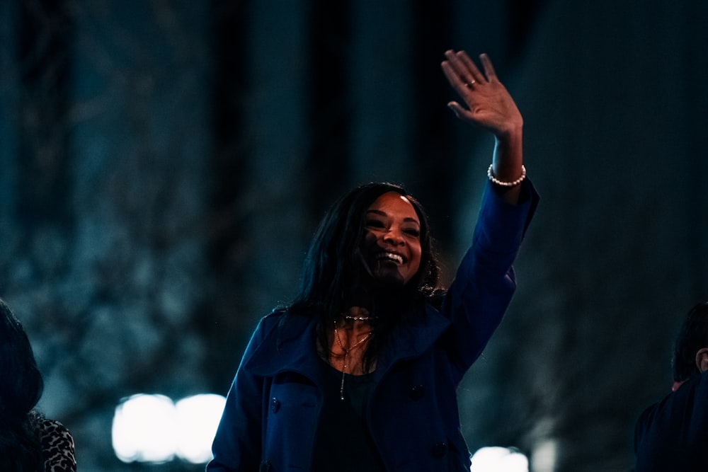 a woman waves to the crowd at night