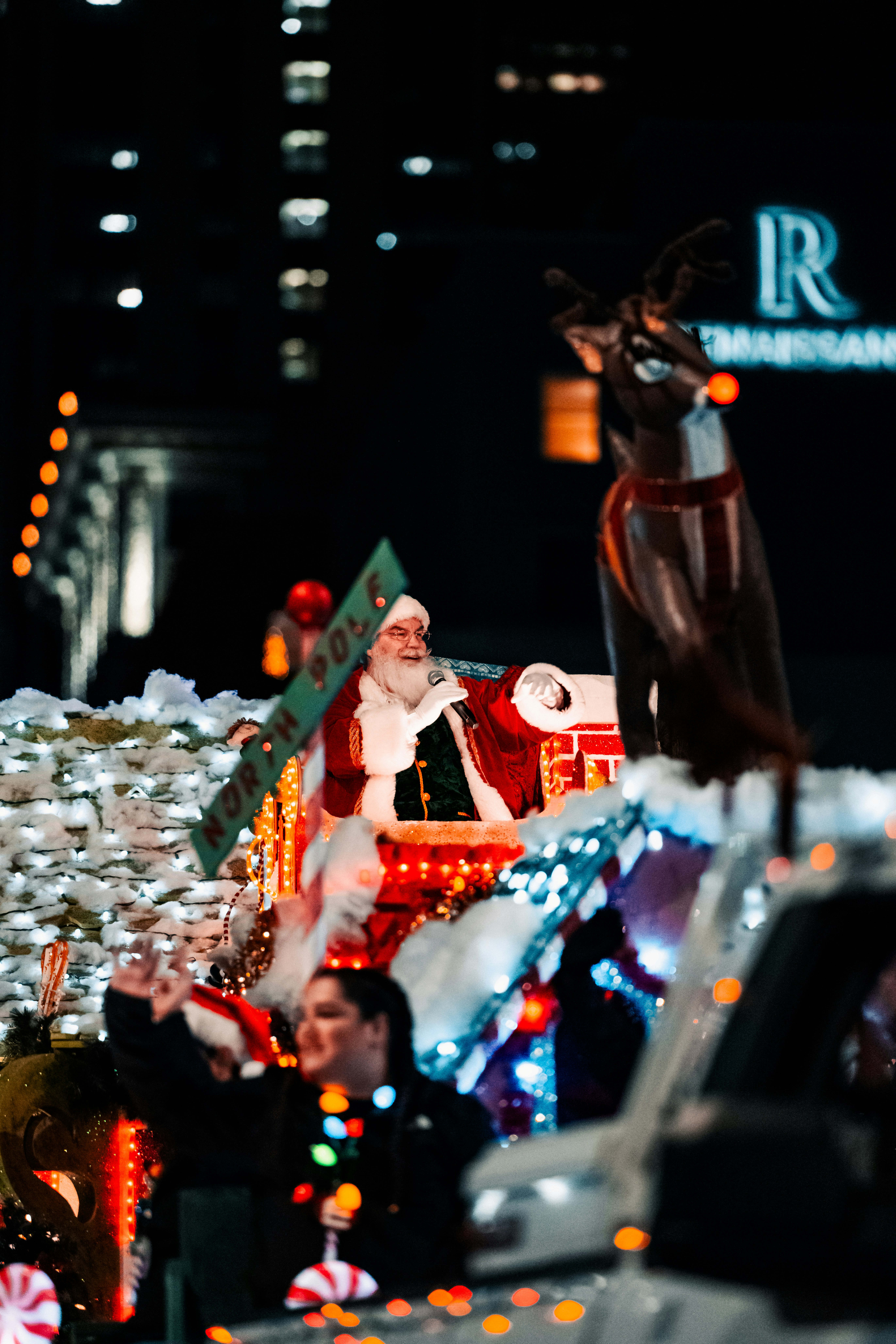 A festive Christmas parade at night with blurry lights.