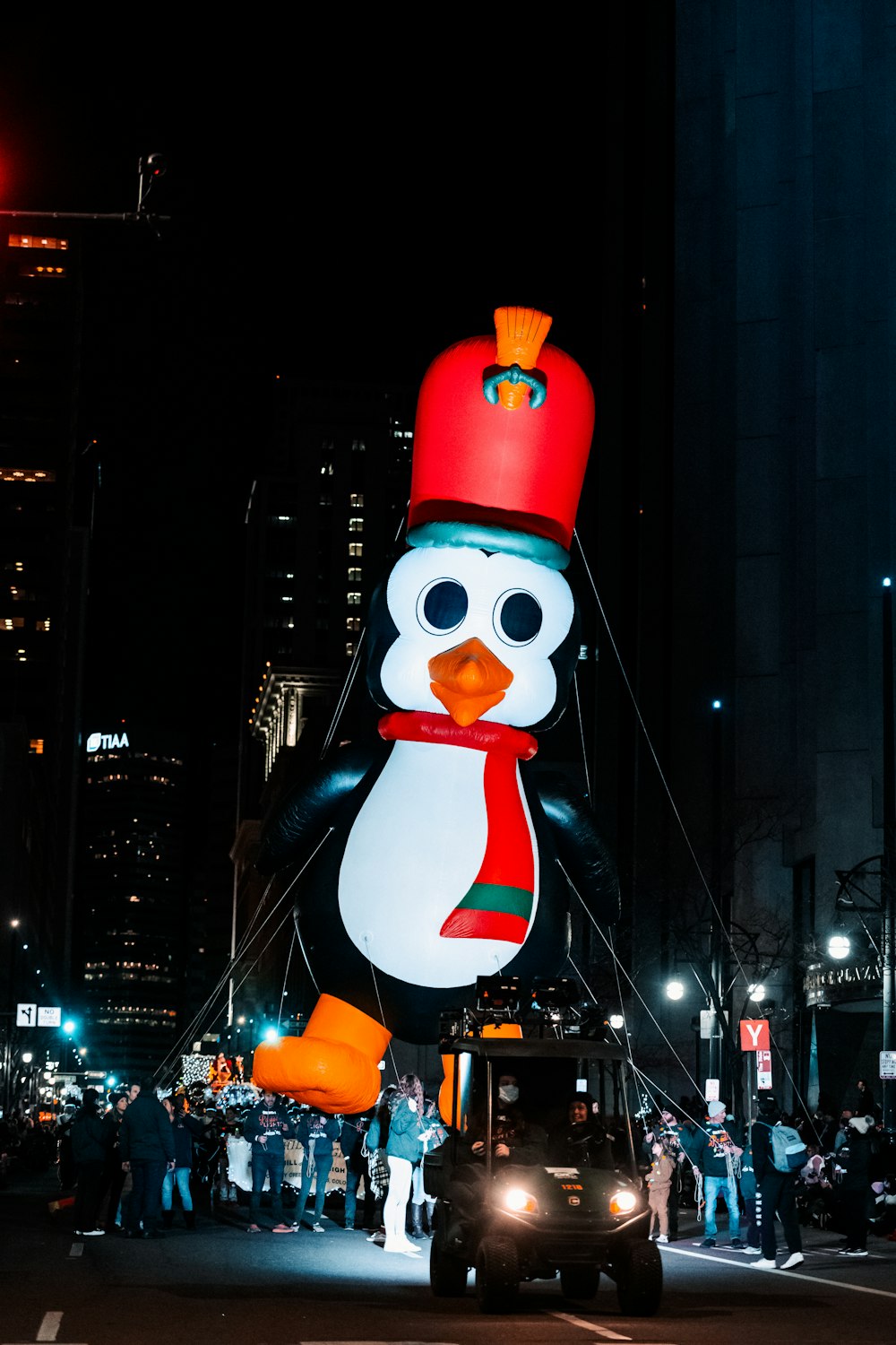a large penguin balloon with a red hat on top of it