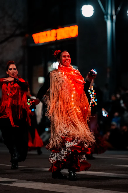 A quinceañera girl smiling brightly as she dances surrounded by friends and family under elegant lighting