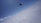 A skydiver is free-falling above a thick layer of clouds against a backdrop of clear blue sky.