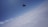 A skydiver is free-falling above a thick layer of clouds against a backdrop of clear blue sky.