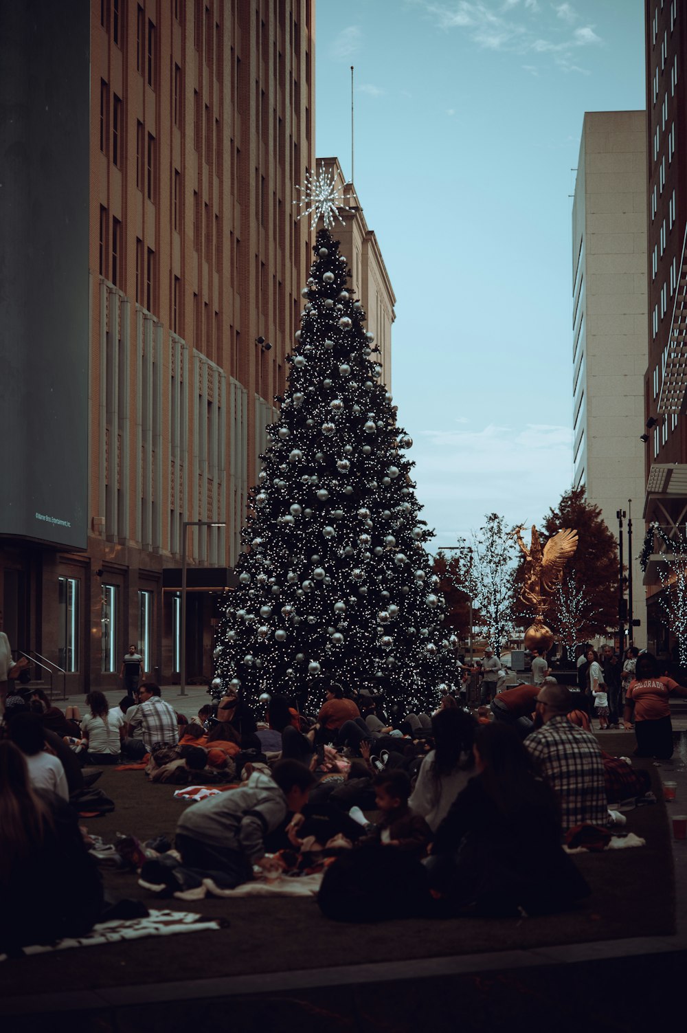 a crowd of people sitting around a christmas tree