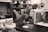 A busy kitchen with workers preparing tortillas and using machinery.