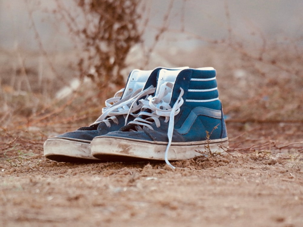 a pair of blue and white shoes sitting on top of a dirt field