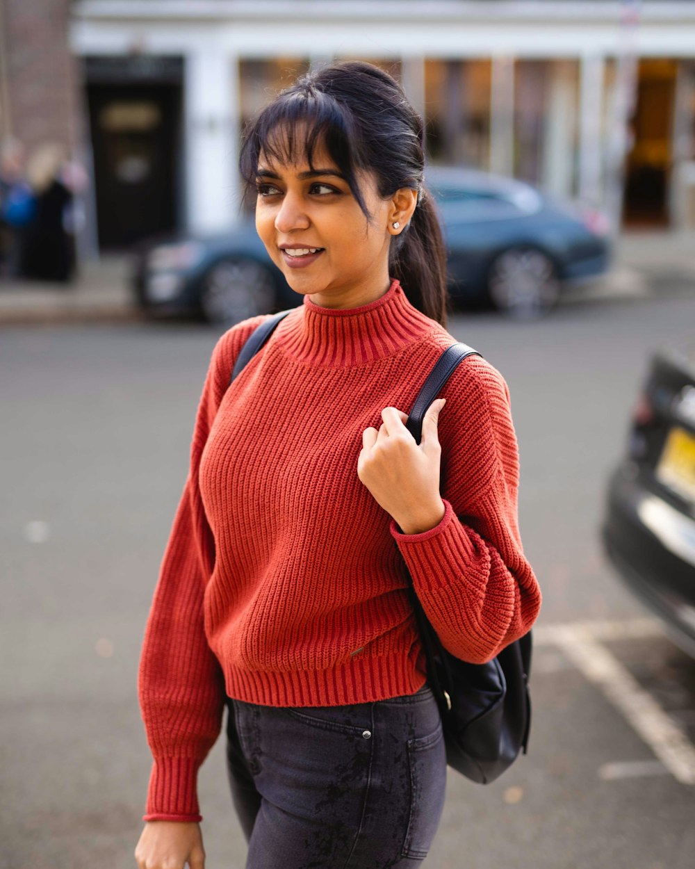 a woman in a red sweater is walking down the street