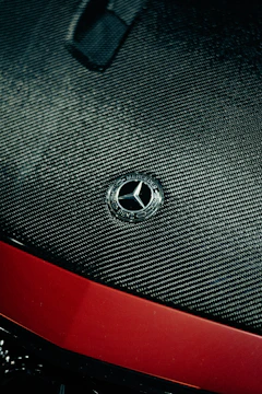 Close-up of a carbon fiber hood with sleek metallic silver finish under soft lighting.