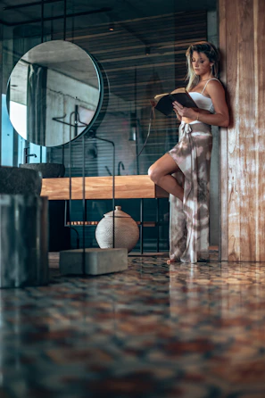 A candid shot of a woman reading the book in a cozy, elegant room with deep black and ivory tones.