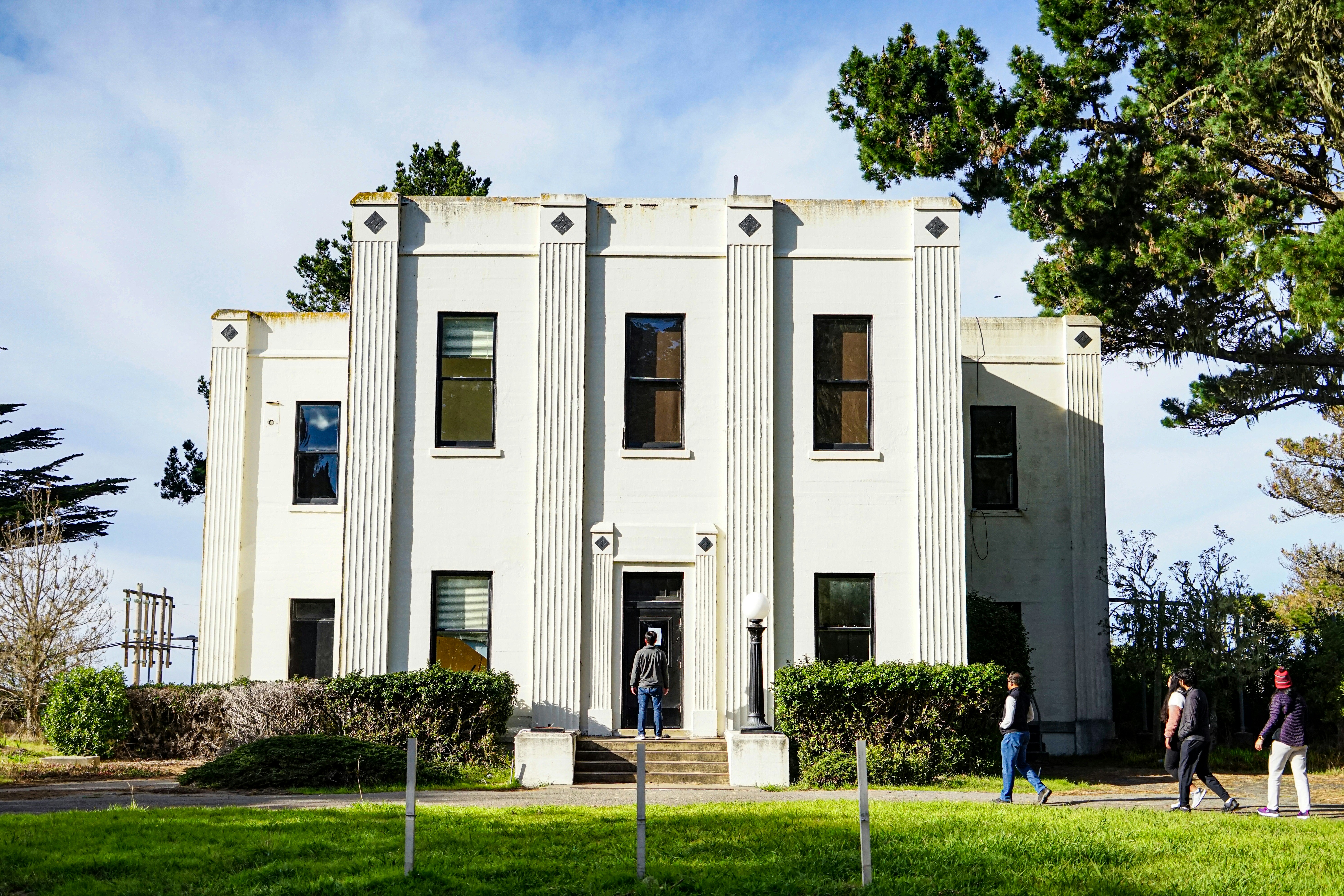 a group of people walking in front of a white building