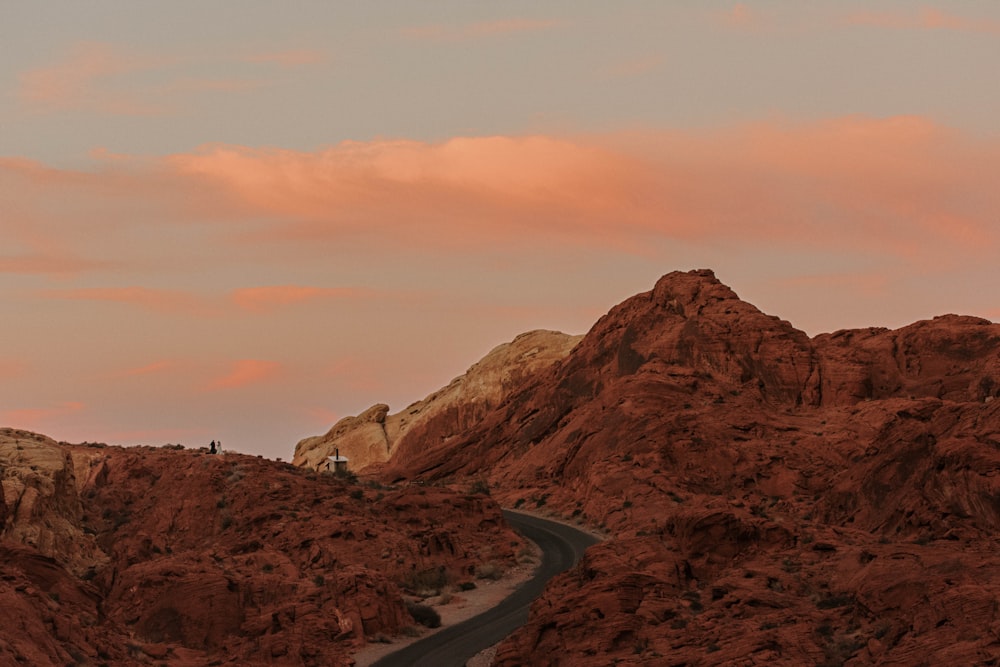 a winding road in the desert with a mountain in the background