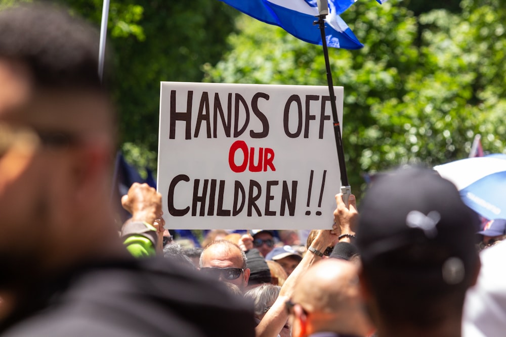 a protest with a sign that reads hands off our children