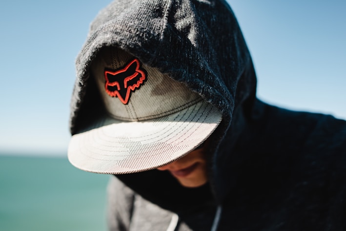 a man wearing a hat with a red fox embroidered on it