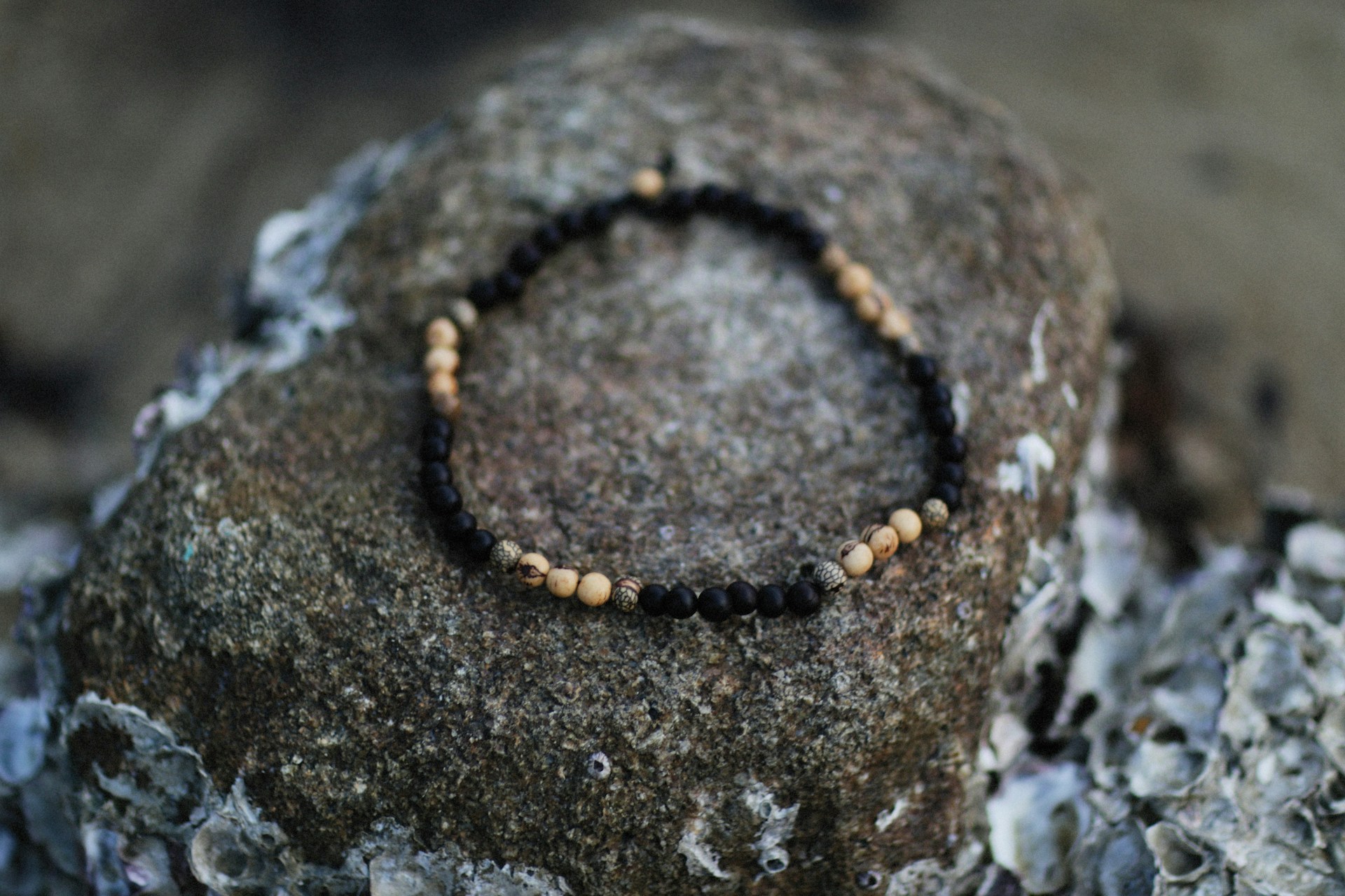 a beaded bracelet sitting on top of a rock