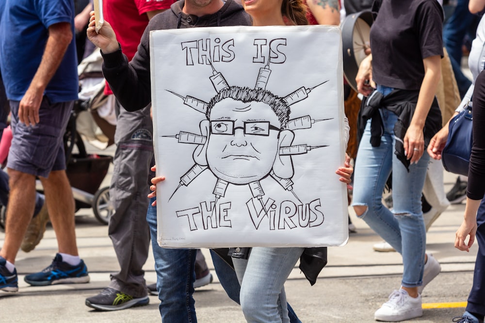 a woman holding a sign that says this is the weird