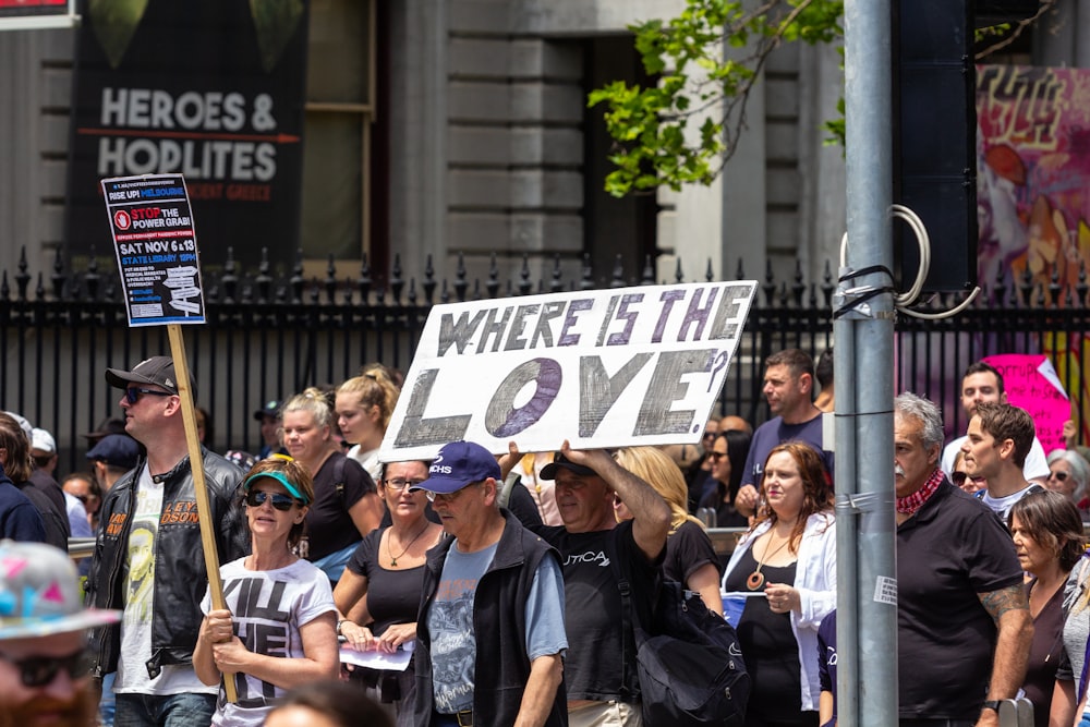 a group of people walking down a street holding signs