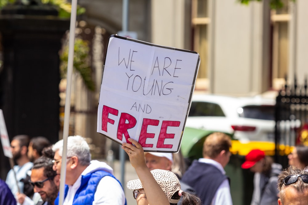 a person holding a sign that says we are young and free