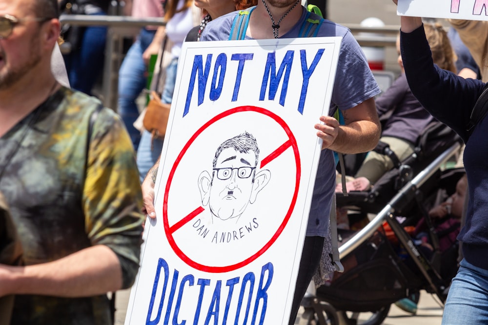 a man holding a sign that says not my dictator