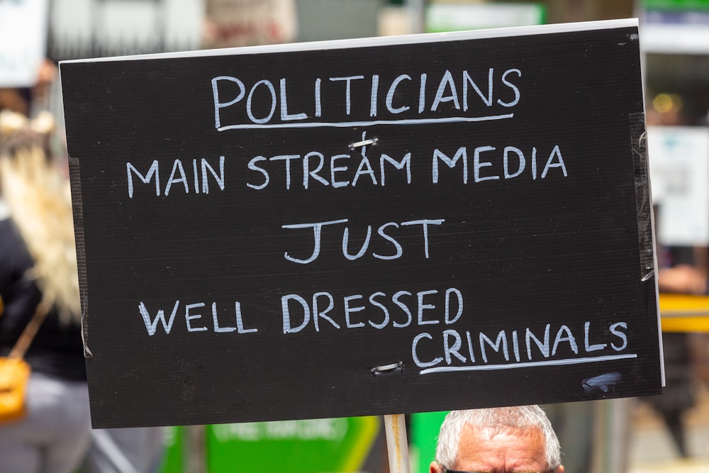 政治家の主流メディアがちょうどよく服を着たという看板を持っている男 クリミ