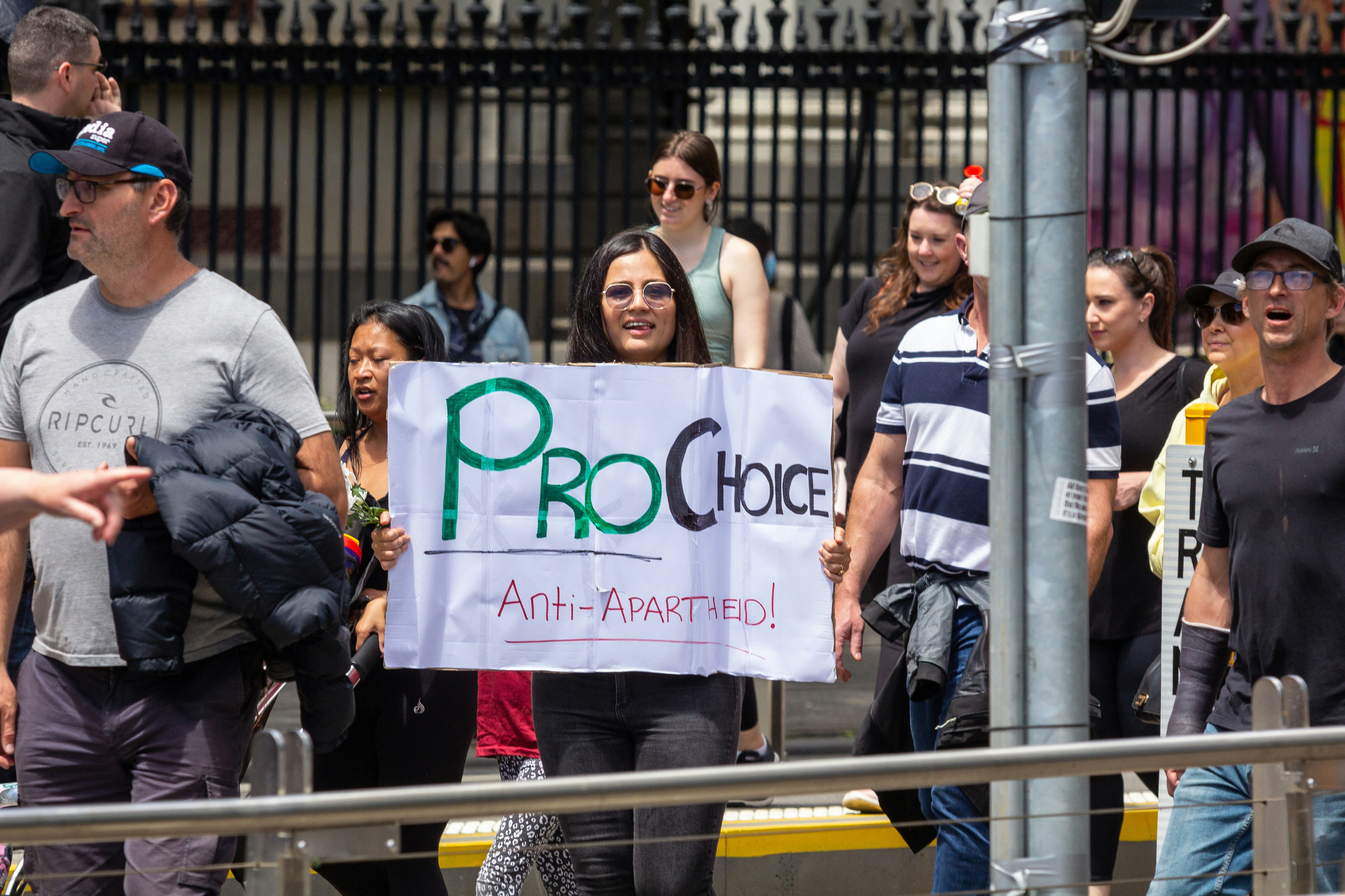 a group of people walking down a street holding a sign