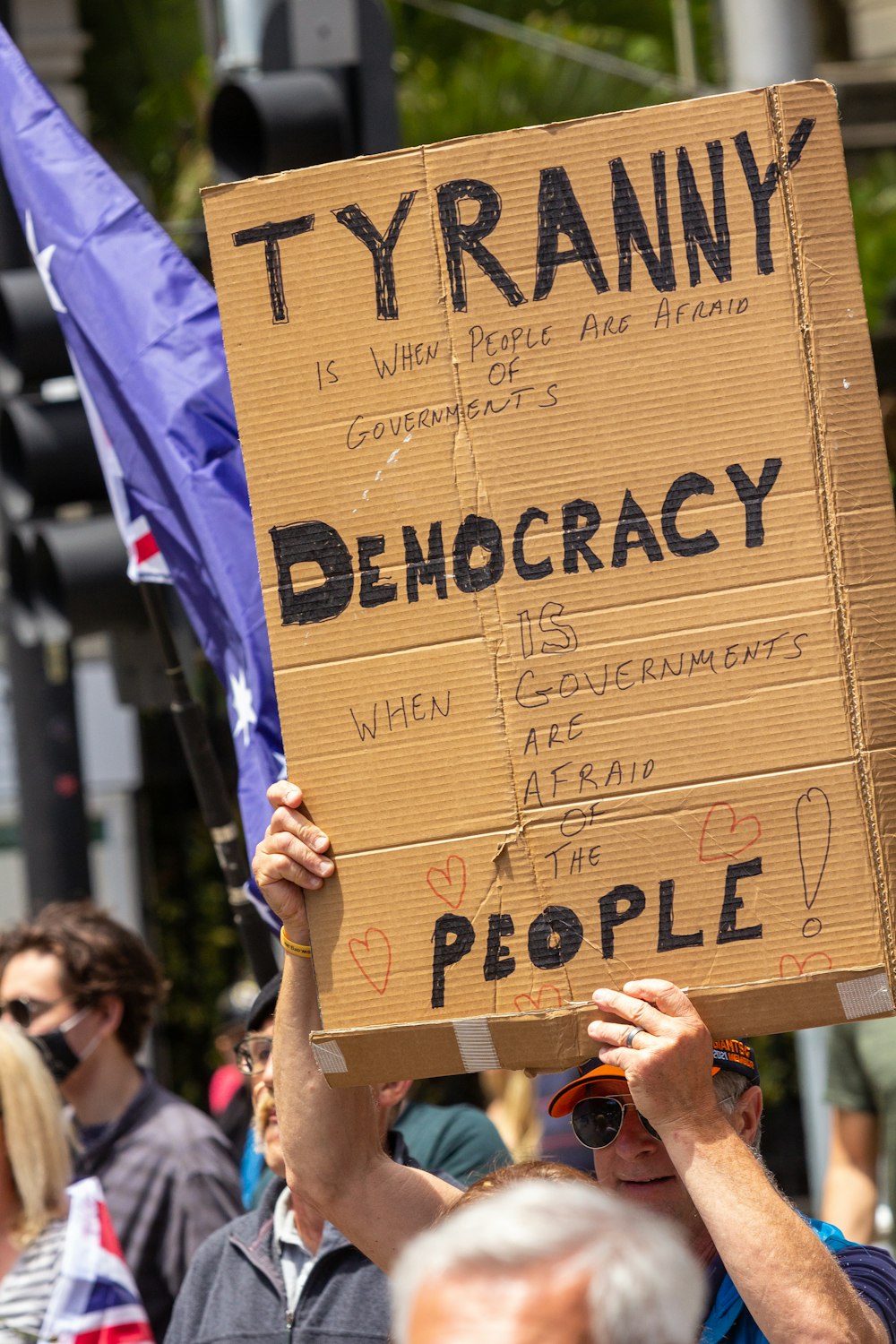 a man holding a sign that reads tyranny democracy