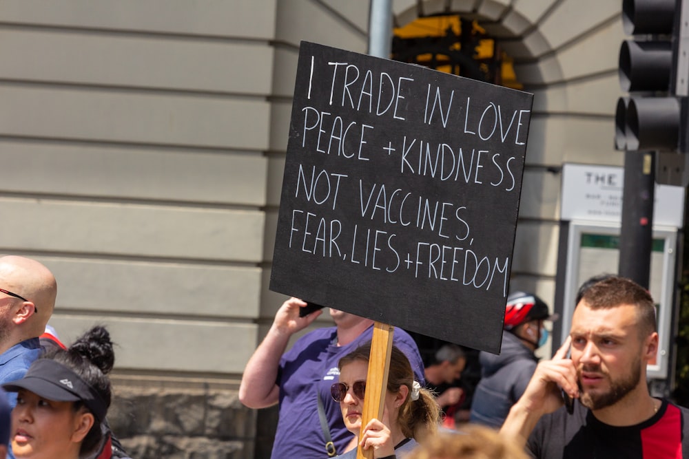 a man holding a sign that says it trade in love peace and kindness not va