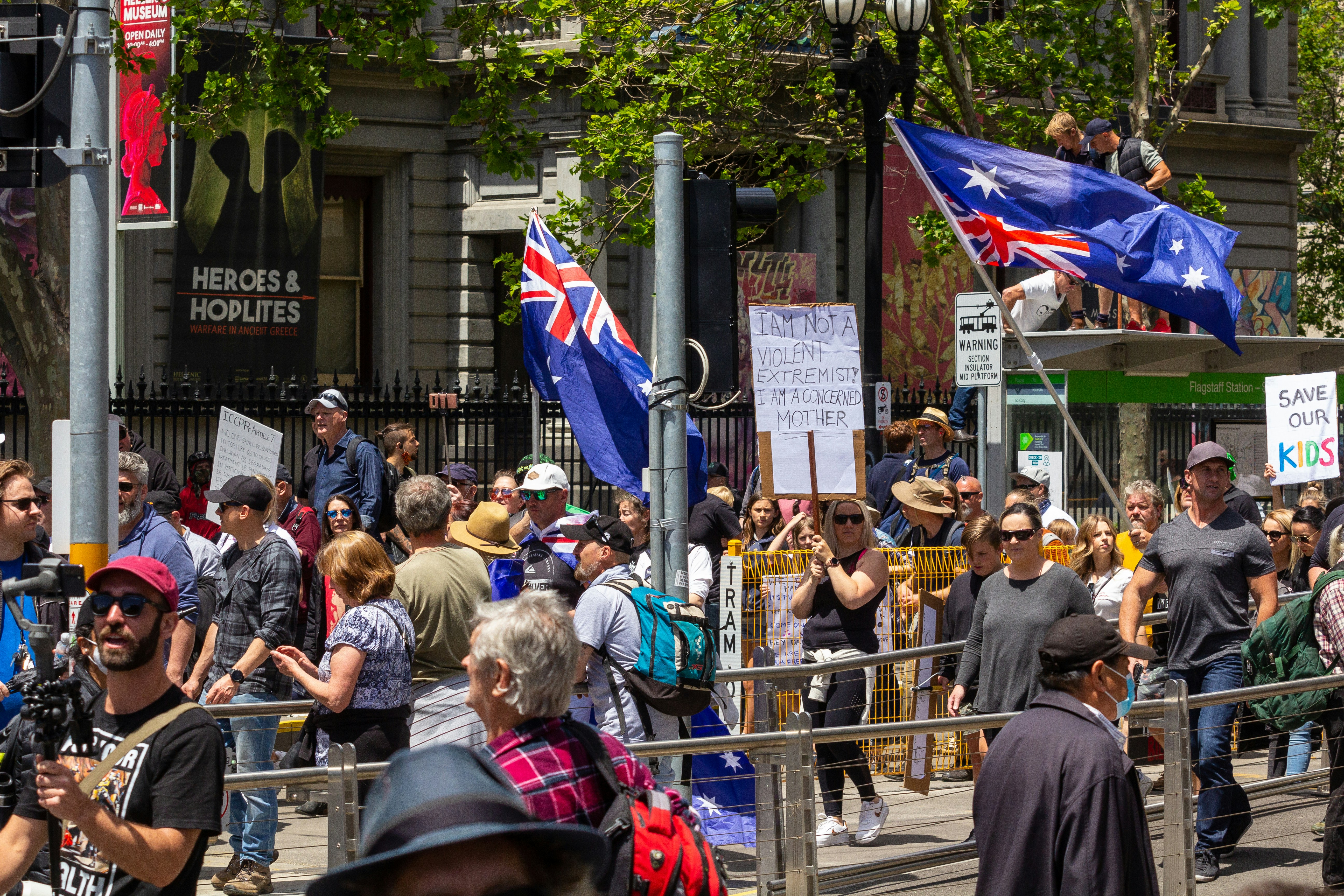 a crowd of people walking down a street next to tall buildings