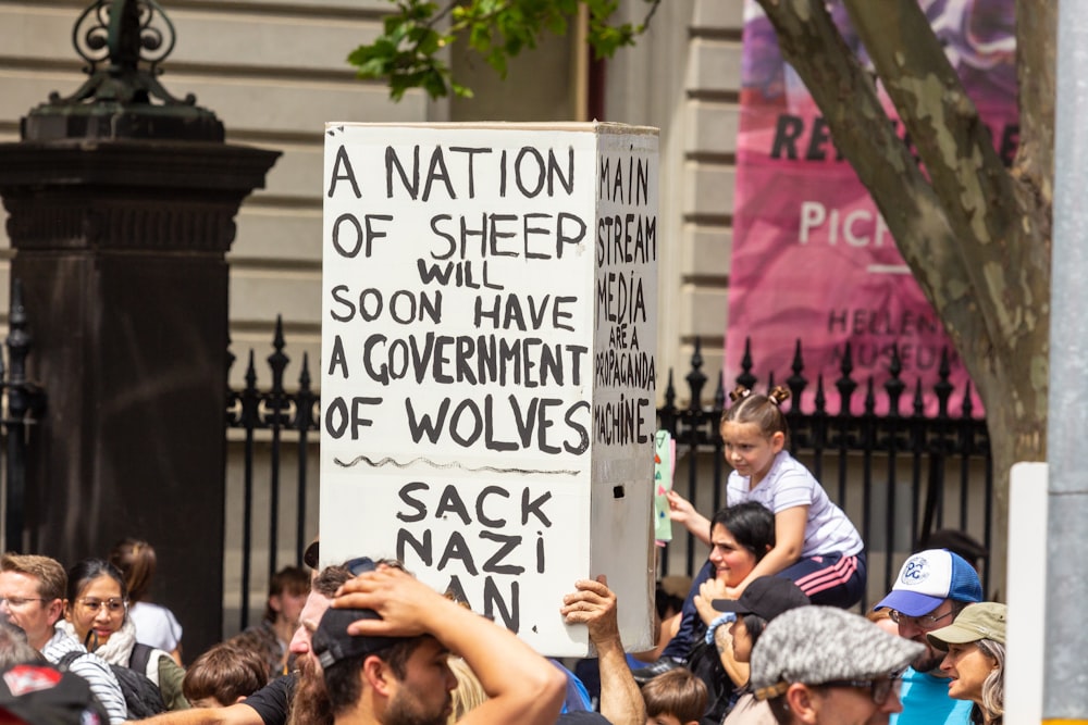 a crowd of people holding signs in front of a fence