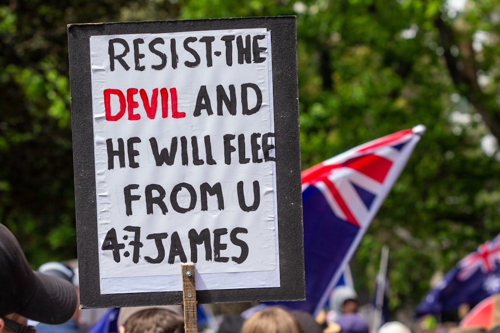 Una protesta con un cartel que dice Resistiendo al diablo y huirá de U
