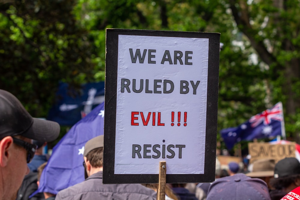 a protest sign in front of a crowd of people